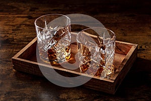 Whiskey in glasses with ice. Bourbon whisky on rocks on a dark rustic background photo
