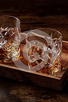 Whiskey in glasses with ice. Bourbon whisky on rocks on a dark wooden table photo