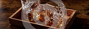 Whiskey in glasses with ice panorama. Bourbon whisky on rocks on a dark table photo