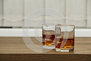 Whiskey with ice or brandy in a glass and a square carafe on an old wooden background. Whiskey with ice in a glass. Whiskey or cog