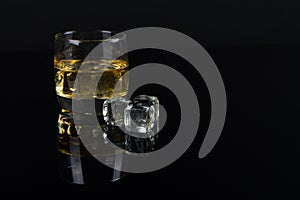 Whiskey with ice in glass on black background. old oak barrel