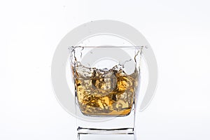 Whiskey with ice. Rum with ice. Brown brandy with ice. Three ice cubes in a glass with alcohol.