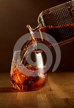 Whiskey is poured into a dammed glass with ice