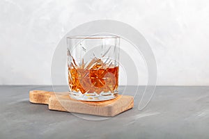 Whiskey on the rocks or scotch with ice cubes. Old fashion glass.    Grey background, copy space