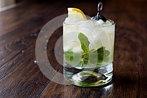 Whiskey Smash Cocktail with Mint Leaves, Lemon, Olive and Crushed Ice.