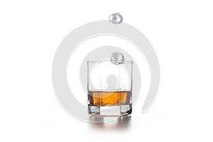 Whiskey splash from the fallen ice cube into glass with beverage on light background