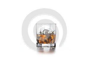 Whiskey splash from the fallen ice cube into glass with beverage on light background