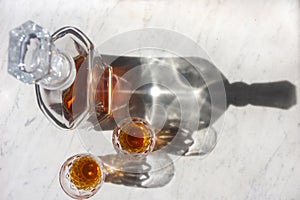 Whisky decanter and two glasses on a marble background top down view with shadows