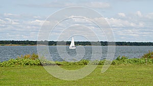 A whit sail boat floating on Grapevine lake Texas.