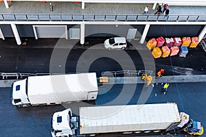 White 18 eighteen wheeler delivery trailer parked loading/ unloading boxes/ packages from/ to forklift.