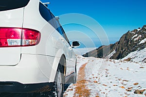 A white 4x4 transfer car on a snow mountain road. Blue sky