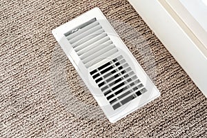 White air conditioner duct grille cover against floor with brown carpet