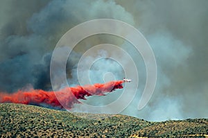 White Aircraft Dropping Fire Retardant as it Battles the Raging Wildfire photo
