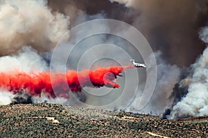 White Aircraft Dropping Fire Retardant as it Battles the Raging Wildfire photo