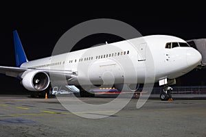 White aircraft on the parking area in the airport at night