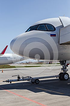 White airplane on runway at airport. Nose part. Modern aircraft on ground. Aviation Russian flag