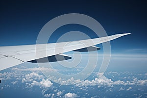 White airplane wing in the blue sky with scattered white clouds