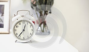 White alarm clock on bedside table. Close up