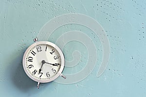 White alarm clock on the blue textured table