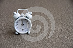 White alarm clock isolated on marble floor The clock set at 12 o'clock.
