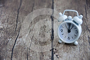 White alarm clock isolated on wooden desk. The clock set at 11 o'clock. photo