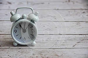 White alarm clock isolated on wooden desk. The clock set at 11 o'clock. photo