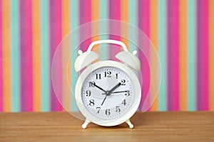 White alarm clock on a multicolored background