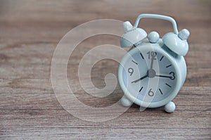 White alarm clock pointing at 8am on wooden table. Copy space and time concept