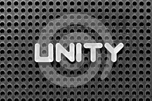 White letter in word unity on black pegboard background