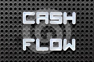 White alphabet with word cash flow on black pegboard background