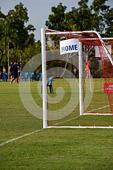A white aluminum goal with orange net for a youths football pitch.