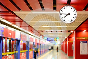 White analog clock in red urban subway station