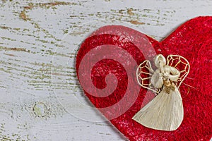 White angel on a red heart. Postcard Happy Valentine`s Day. Light wooden background, place for text, Valentine card.