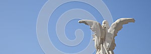White angel with wings against blue sky. Ancient statue