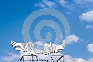 White angel wings on bright blue sky clouds vast space background