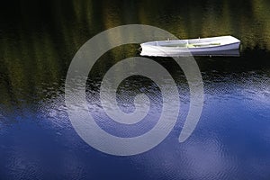 White angelic single lonely boat floating peaceful bliss mindfulness in calm water with blue sky reflection sun shinning brightly