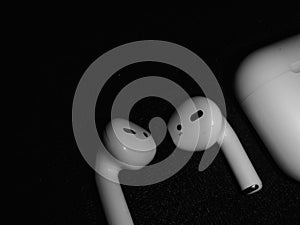 A white apple earbuds are next to a white apple.
