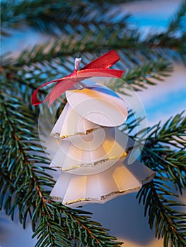 White aromatic candle in the shape of a decorative Christmas tree on a fir branch