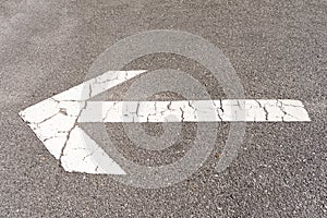 White arrow on the asphalt floor of a parking lot to direct traffic