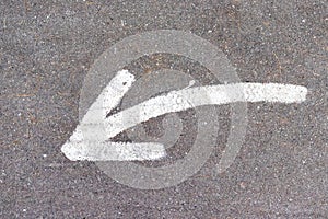 White arrow on asphalt road showing down