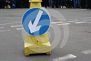 White arrow on blue traffic sign on road