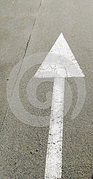 White arrow indicating the direction of movement on an asphalt road