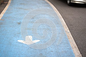 White arrow sign on blue road with line and movement car in park