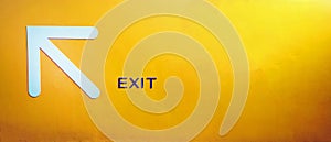 White arrow sign give direction to go up, entrance, exit or way on yellow concrete wall with copy space. Traffic symbol
