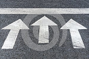 White arrows on black highway asphalt, pedestrian crossing road marking fragment