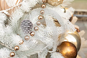 White artificial Christmas tree decorated with a silver cone, shiny balls and a golden garland. Festive New Year background