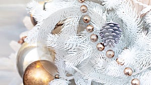 White artificial Christmas tree decorated with a silver pine cone, shiny balls and a golden shimmering garland. festive Christmas