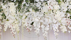 White artificial flowers hang in the banquet hall as decoration for a holiday, close-up