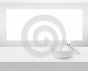 White ashtray and cigarette on white wooden table with copy space