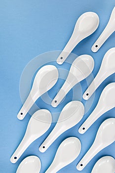 White Asian style spoons arranged in an abstract pattern on blue background